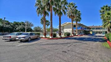 A parking lot with a building that has a blue awning and a red curb.