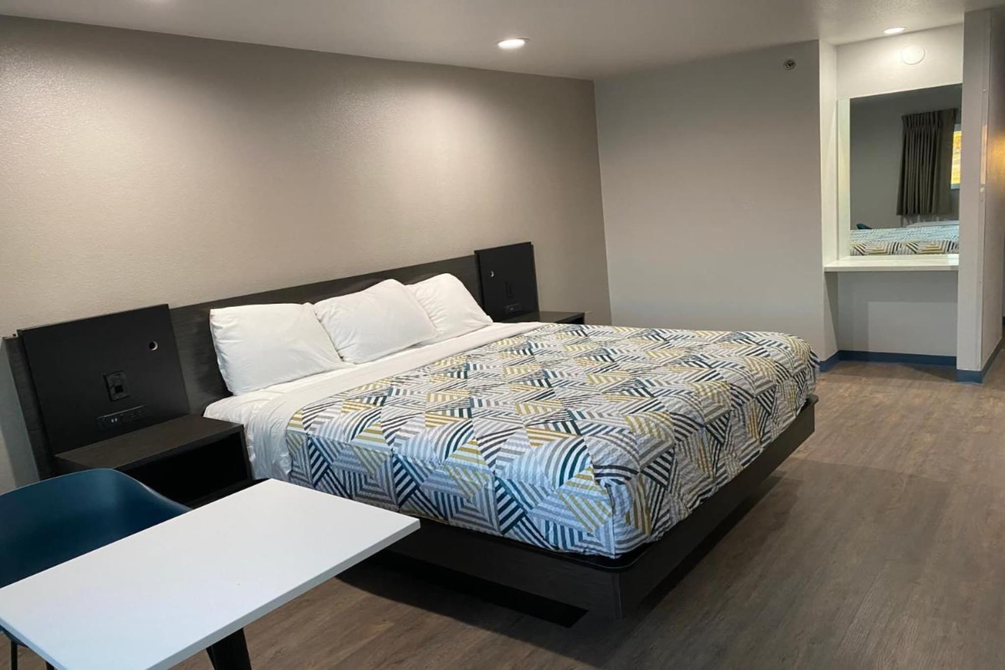 Ein Hotelzimmer mit Bett, Nachttisch und kleinem Schreibtisch.