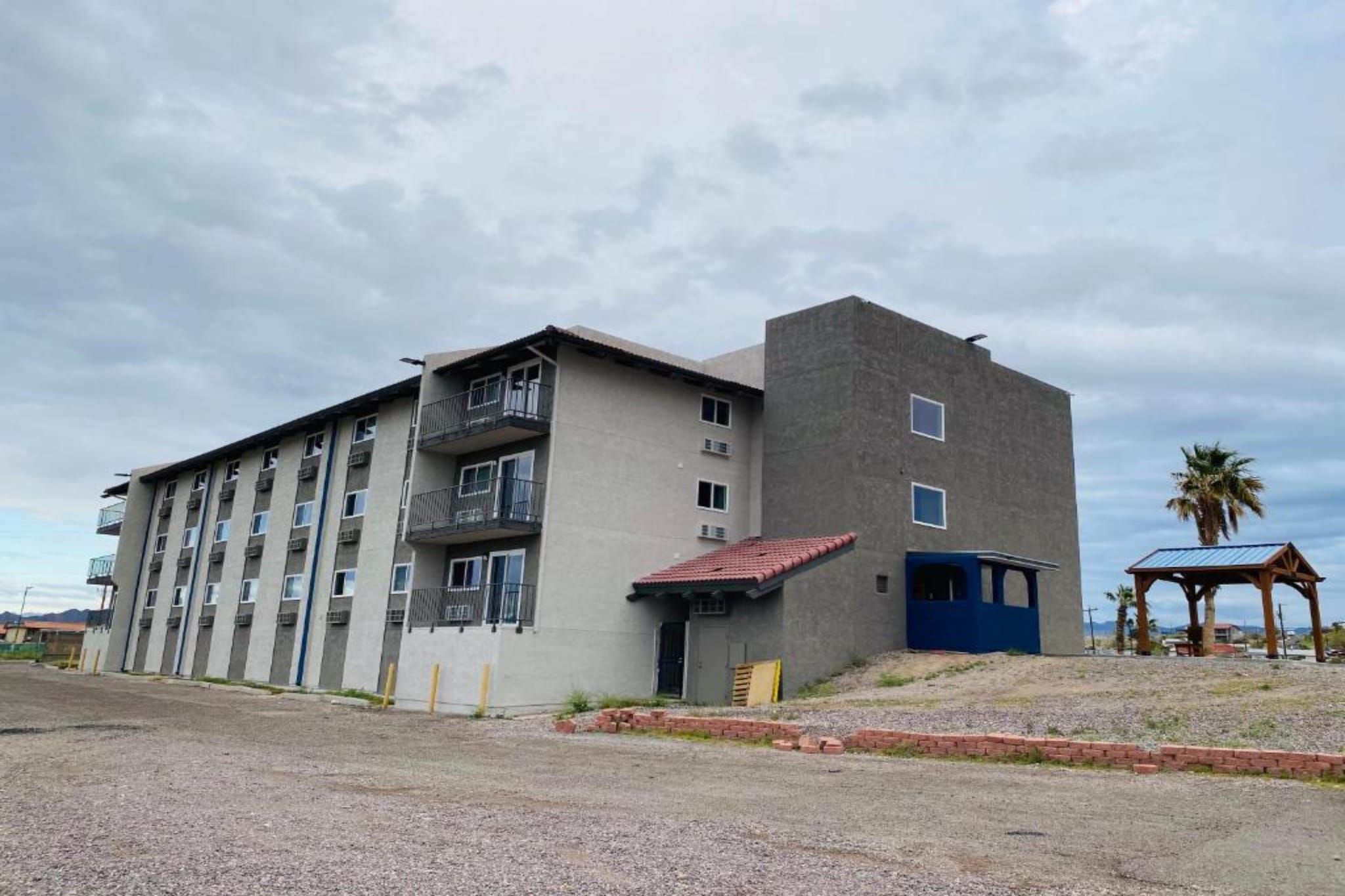 Un edificio de varios pisos con balcones y una pequeña construcción adosada con techo rojo.