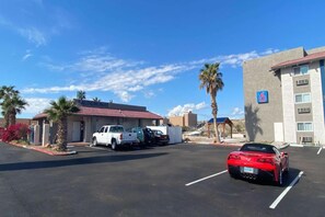 Un estacionamiento con un edificio que dice 'AUNDROMAT' y un auto deportivo rojo estacionado al frente.