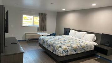 Una camera d'albergo moderna con un letto grande, una scrivania, una sedia, una televisione e una finestra con tende.