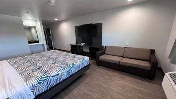 Quarto moderno com cama, sofá, televisão e guarda-roupa.