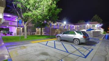 A parking area with a car, a building with a ramp, and a tree.