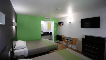 A hotel room with a bed, a desk, a chair, a television, and a wardrobe.