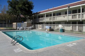 A swimming pool with a metal ladder, surrounded by a white fence, and a building with balconies in the background. - 2 Queen Beds | Non-Smoking, Kitchen (Barstow)