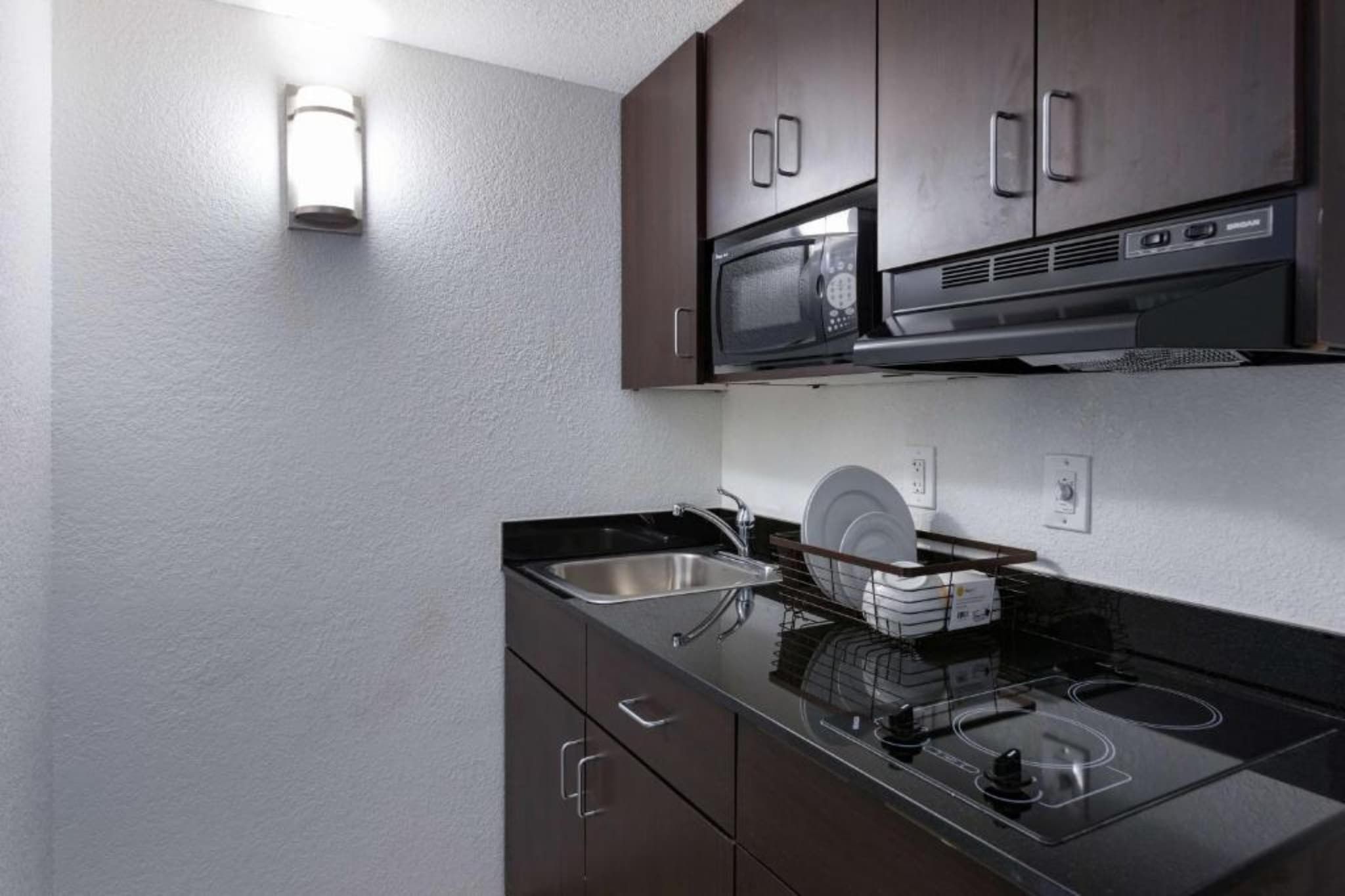 A compact kitchenette with a microwave, stove, and sink.