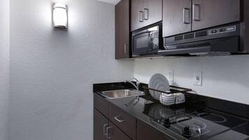 A compact kitchenette with a microwave, stove, and sink.
