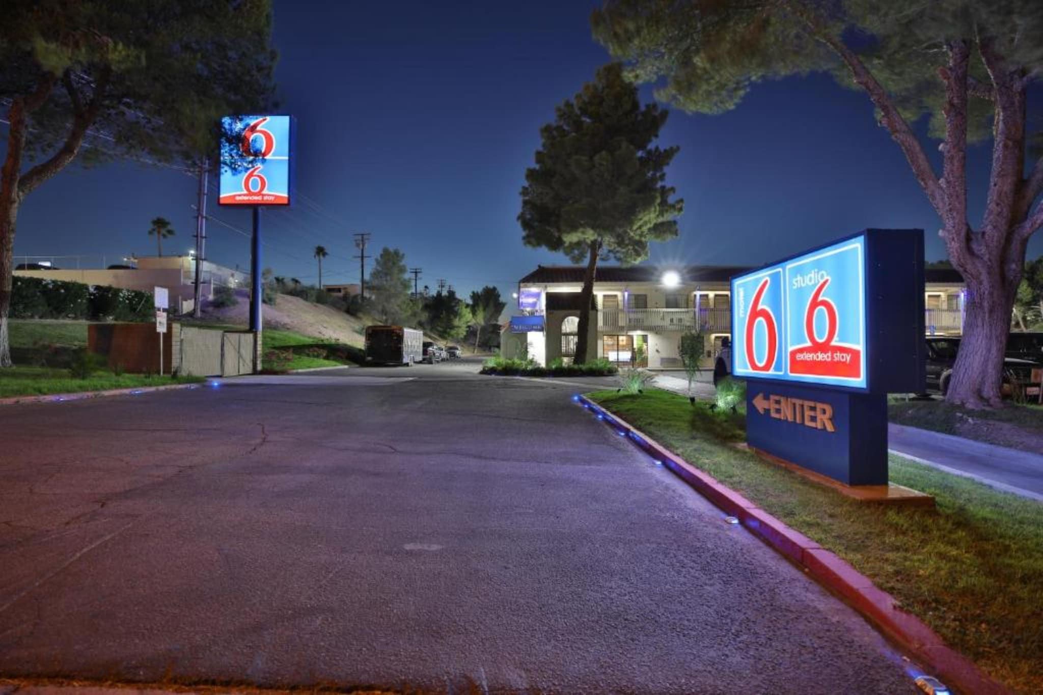A 6 extended stay hotel with a clear entrance, a parking lot, and a building with a lighted entrance.