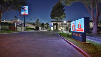 A 6 extended stay hotel with a clear entrance, a parking lot, and a building with a lighted entrance.