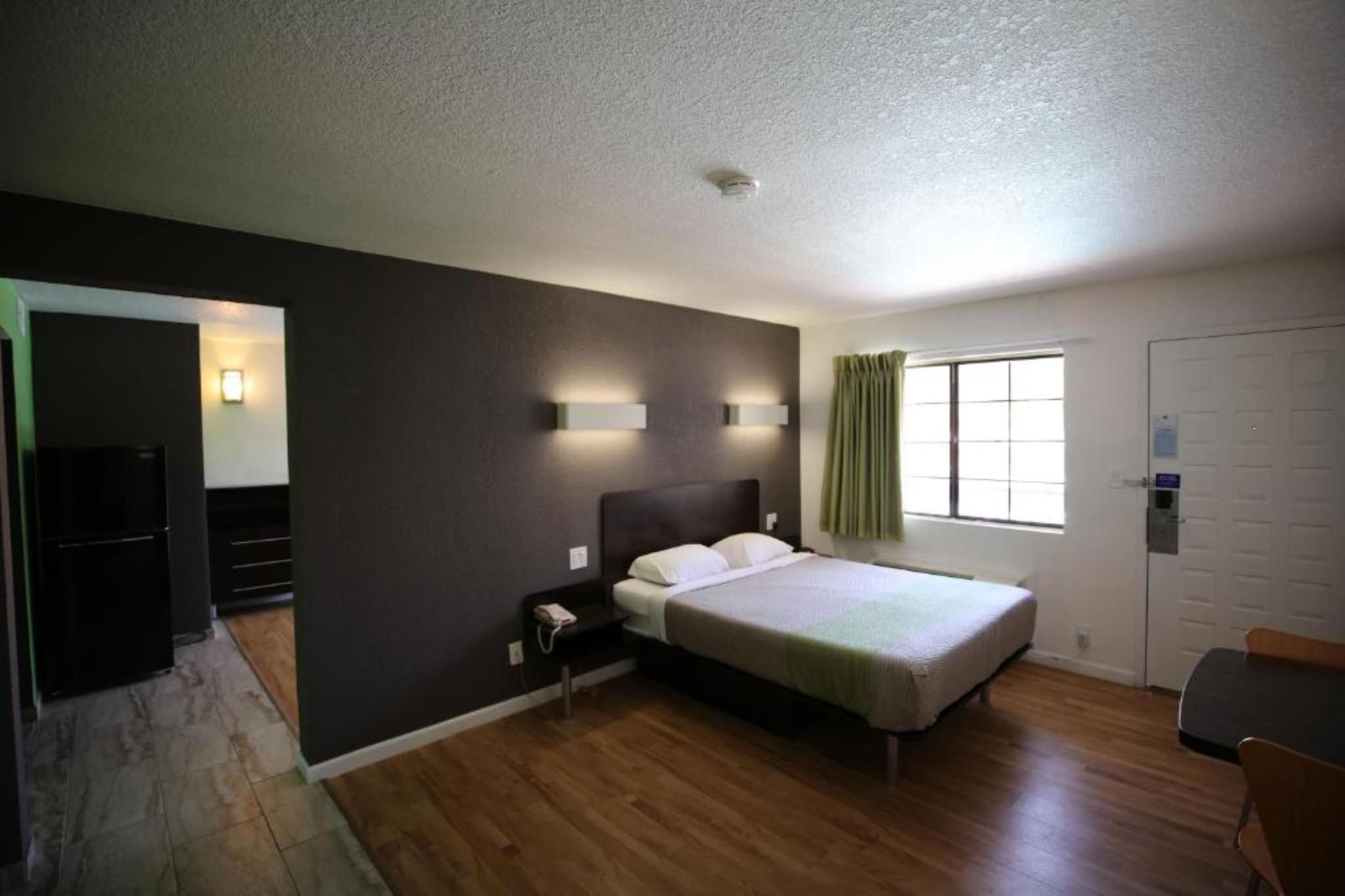 Une chambre à coucher avec un lit, une table de chevet et une fenêtre avec des rideaux.