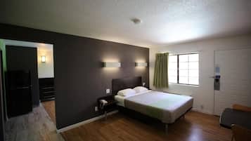 Une chambre à coucher avec un lit, une table de chevet et une fenêtre avec des rideaux.