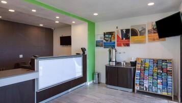 A reception area with a reception desk, a trash bin, a coffee machine, and a magazine rack.