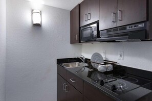 Une petite cuisine équipée d’un four à micro-ondes, d’une cuisinière et d’un évier.