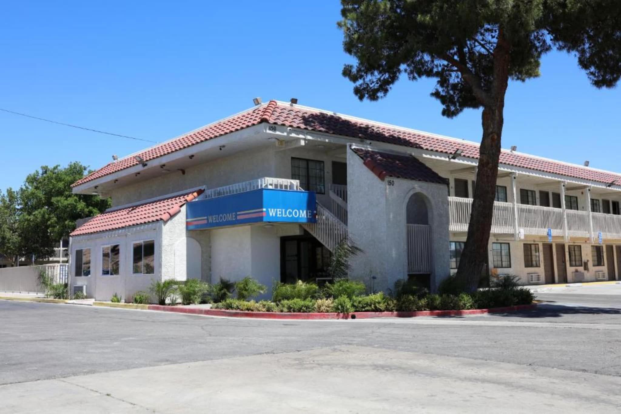 A building with a red-tiled roof, a blue 'WELCOME' sign, and a staircase leading to an entrance.