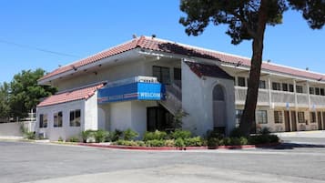 A building with a red-tiled roof, a blue 'WELCOME' sign, and a staircase leading to an entrance.