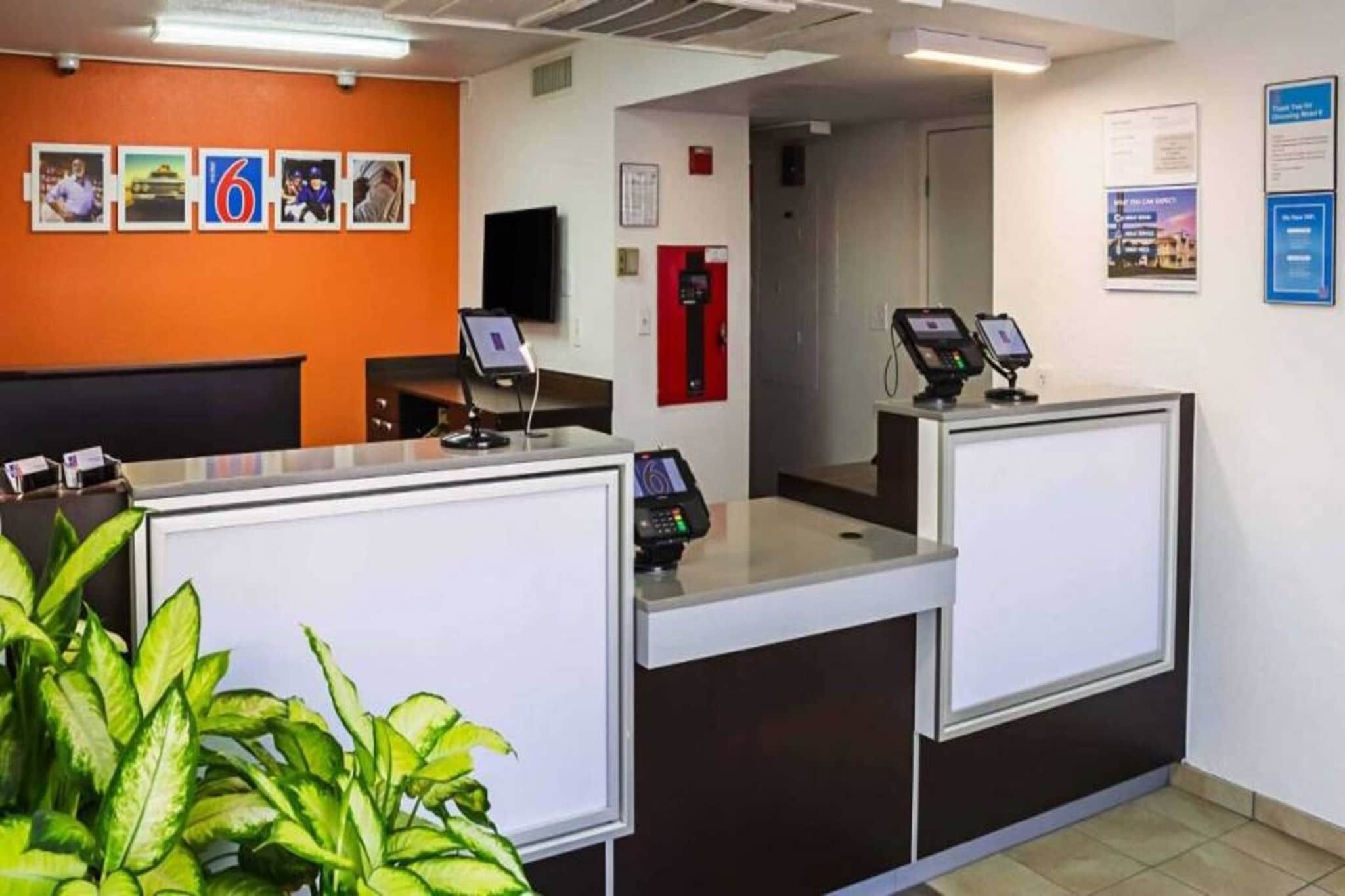 A reception area with two counters, a fire alarm, and a wall with framed pictures.