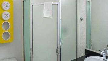 A bathroom with a glass-enclosed shower, a white sink, and a mirror.