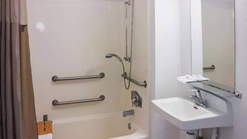 A bathroom with a bathtub, a sink, and a mirror. There are grab bars installed on the tub for safety.