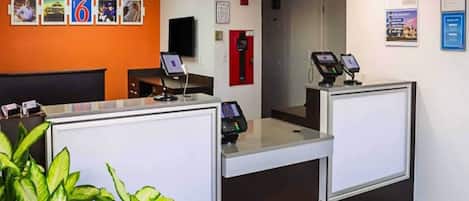 A reception area with two counters, a fire alarm, and a wall with framed pictures.