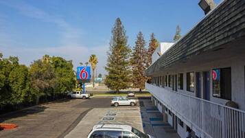 Un motel con un parcheggio, un edificio con un balcone e un cartello con il numero 6.