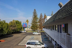 Een motel met een parkeerplaats, een gebouw met een balkon en een bord waarop nummer 6 staat.