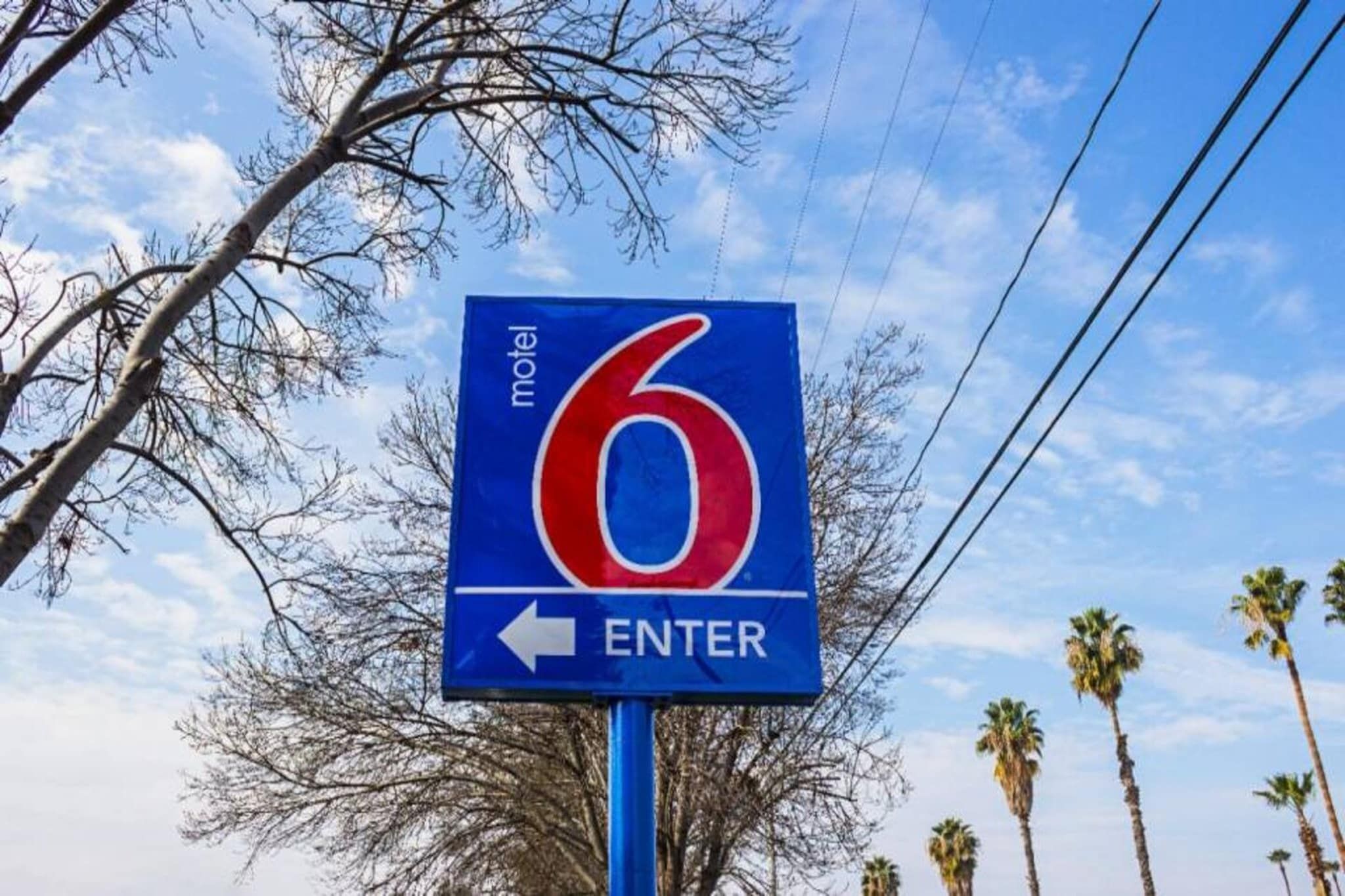 A motel sign with the number 6 and an arrow pointing left, indicating the direction to enter.