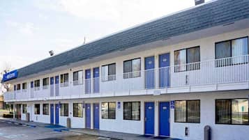 A motel with multiple rooms, a balcony, and a parking lot.