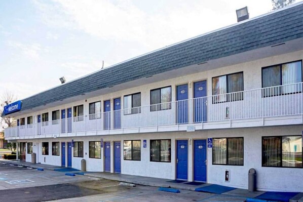 A motel with multiple rooms, a balcony, and a parking lot.
