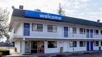 Un motel à deux étages, avec une enseigne « Bienvenue », de nombreuses chambres et un parking.