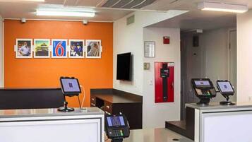 A reception area with a counter, a television mounted on the wall, and a fire extinguisher.