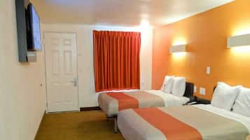 A hotel room with two beds, a television, a door, and a window with curtains.