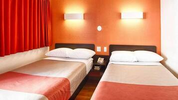 A hotel room with two beds, red curtains, and wall-mounted lights.