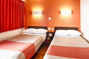 Een hotelkamer met twee bedden, rode gordijnen en wandlampen.