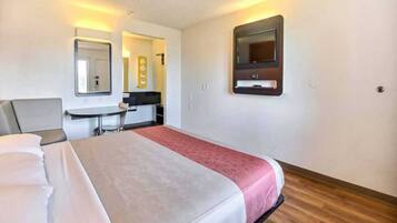 A hotel room with a bed, a desk, and a mirror.