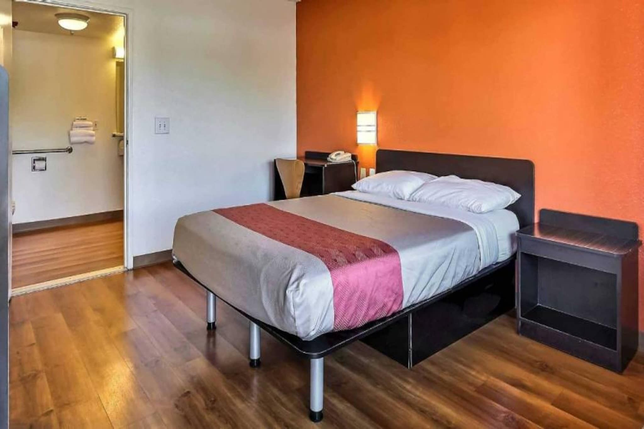 A hotel room with a bed, bedside table, and a nightstand.