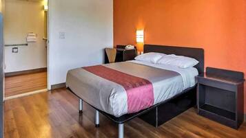 A hotel room with a bed, bedside table, and a nightstand.