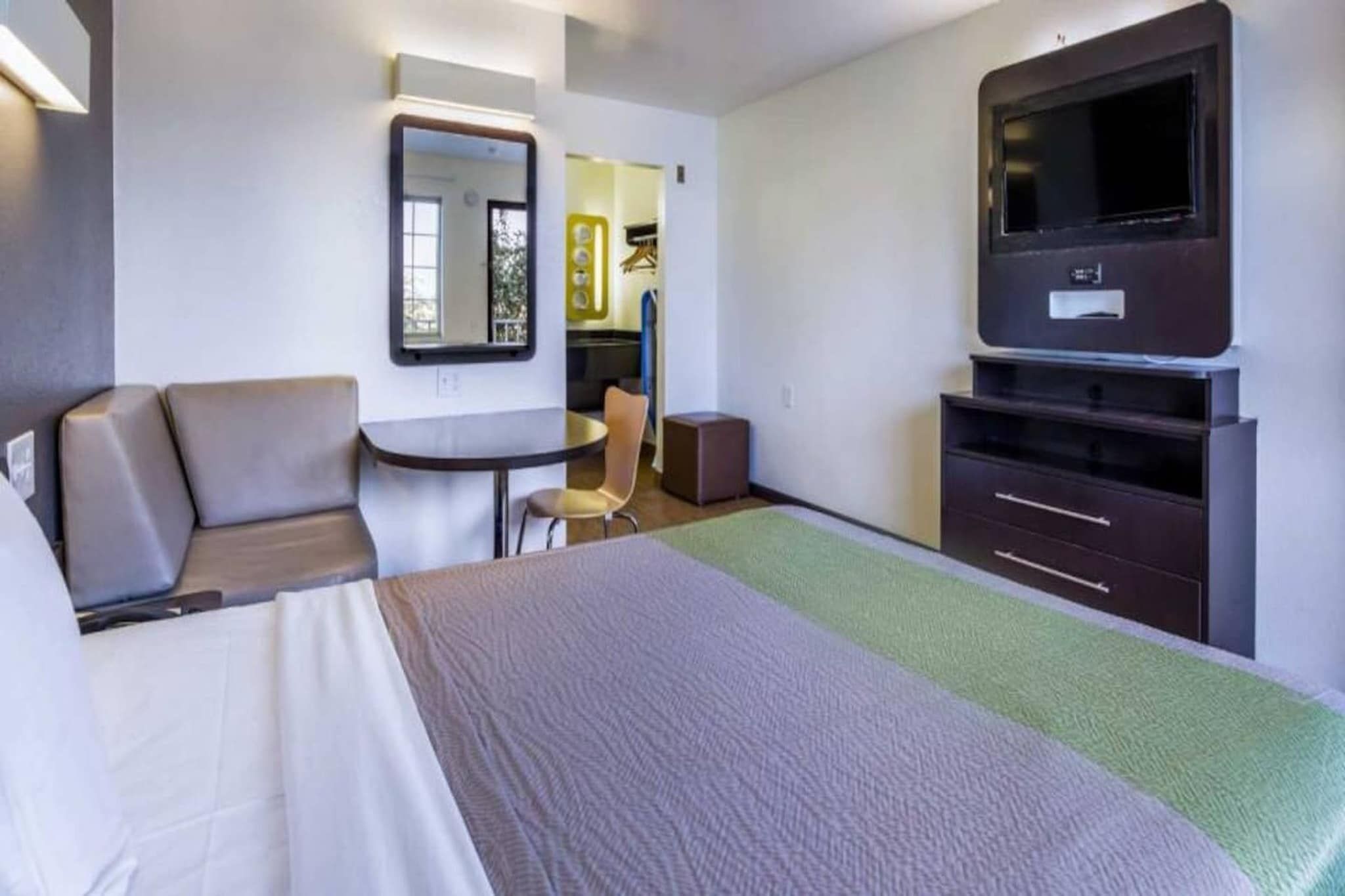 A hotel room with a bed, a desk, a chair, a television, and a wardrobe.