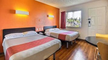 Een hotelkamer met twee bedden, een bureau en een raam met uitzicht.