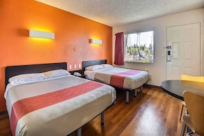Een hotelkamer met twee bedden, een bureau en een raam met uitzicht.