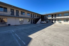 A multi-story motel with a parking lot, a staircase, and a bicycle parked outside. - Cozy Queen Bed|Pool|Free Parking (Williams)