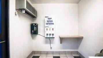 Un baño pequeño y limpio con inodoro, dispensador de jabón y estante.