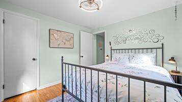 A bedroom with a bed, a world map on the wall, a decorative ceiling light, and a nightstand with a lamp.