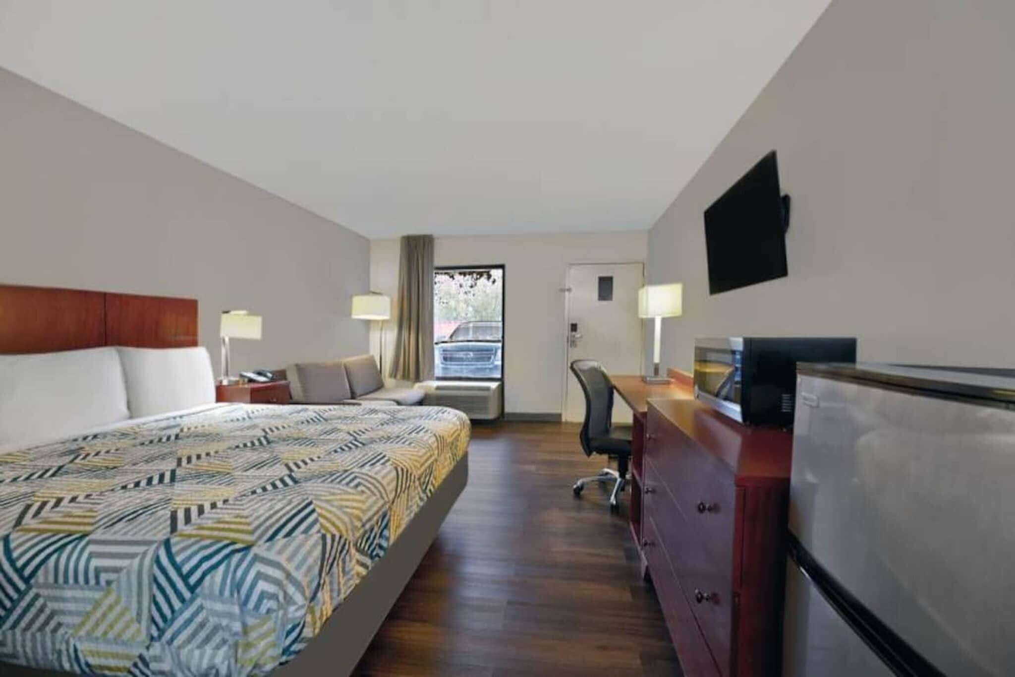 Ein Hotelzimmer mit Bett, Schreibtisch, Stuhl und Fernseher.