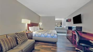 Une chambre d’hôtel comprenant un lit, un bureau, une chaise, un canapé et un téléviseur.