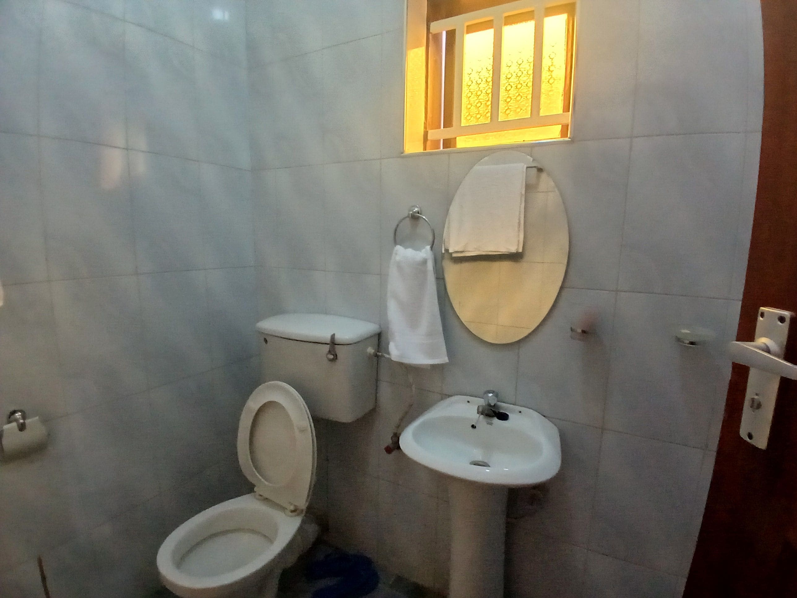 A bathroom with a toilet, sink, and a window with a patterned blind.