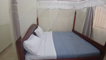 A single bed with a canopy, a wooden headboard, and a blue mattress cover.