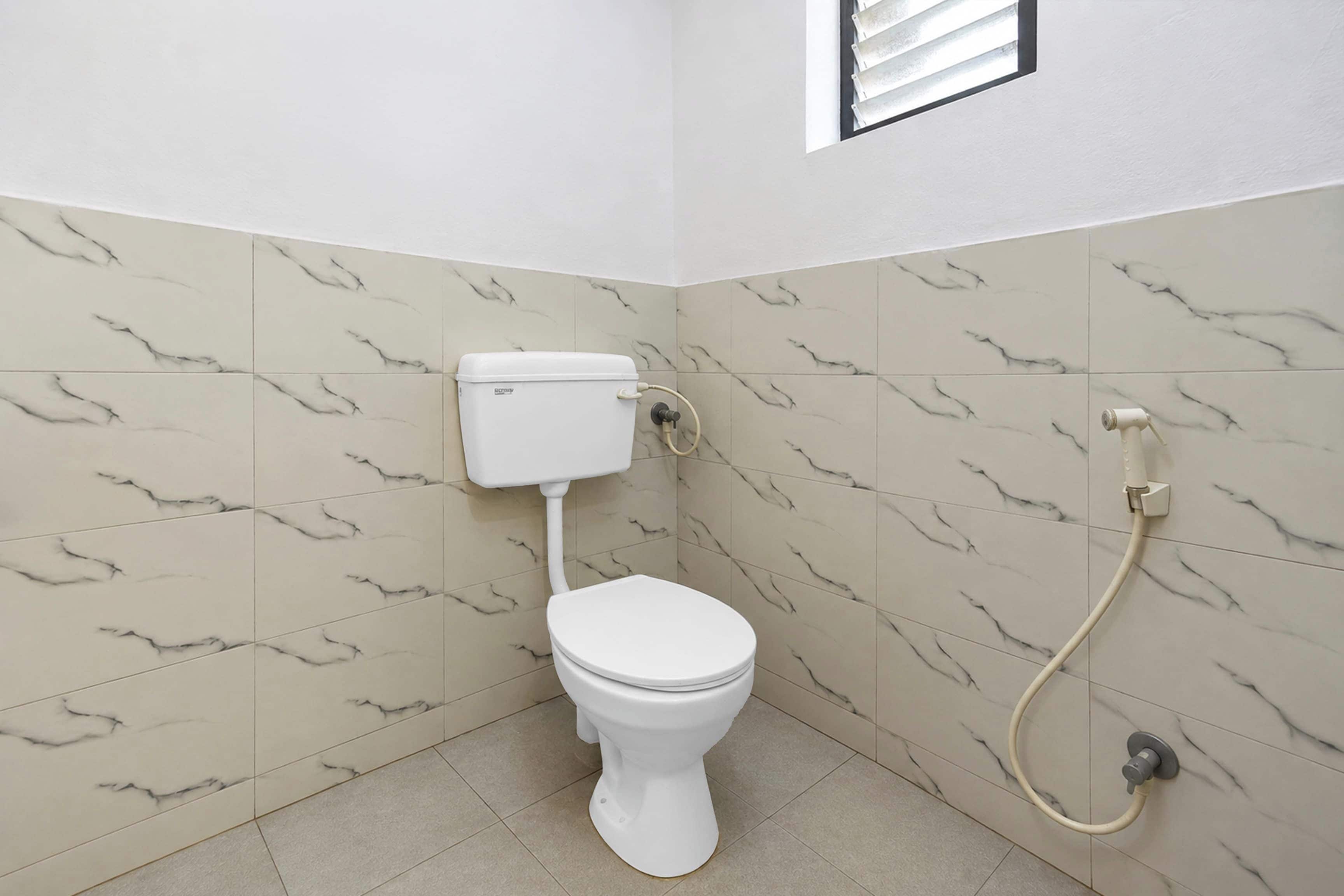 A bathroom with a toilet, a wall-mounted bidet, and a window.