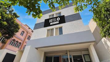 Ein Hotel namens 'HOTEL OYO' mit einer modernen Fassade, großen Fenstern und einem Schild, das anzeigt, dass es von OYO bewirtschaftet wird.
