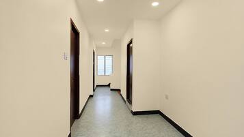 A hallway with a marble floor, white walls, and recessed ceiling lights.