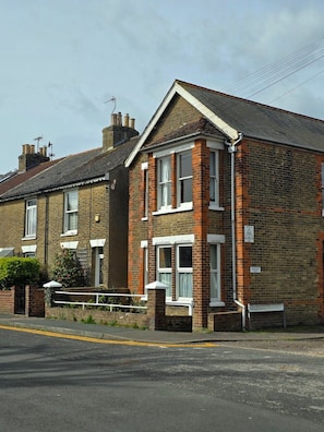 A two-story residential building with a brick facade, multiple windows, and a visible chimney. - Charming, spacious apartment near to the beach. (Walmer)